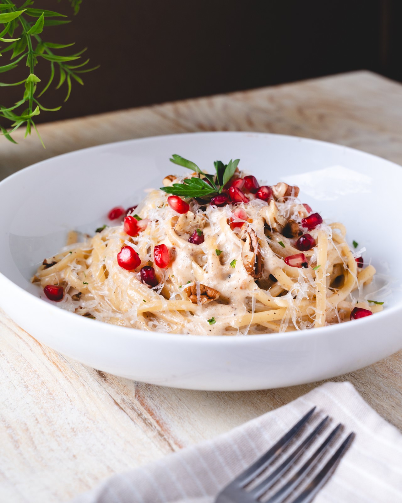Plato de pasta en salsa blanca con granos de granada fresca.
