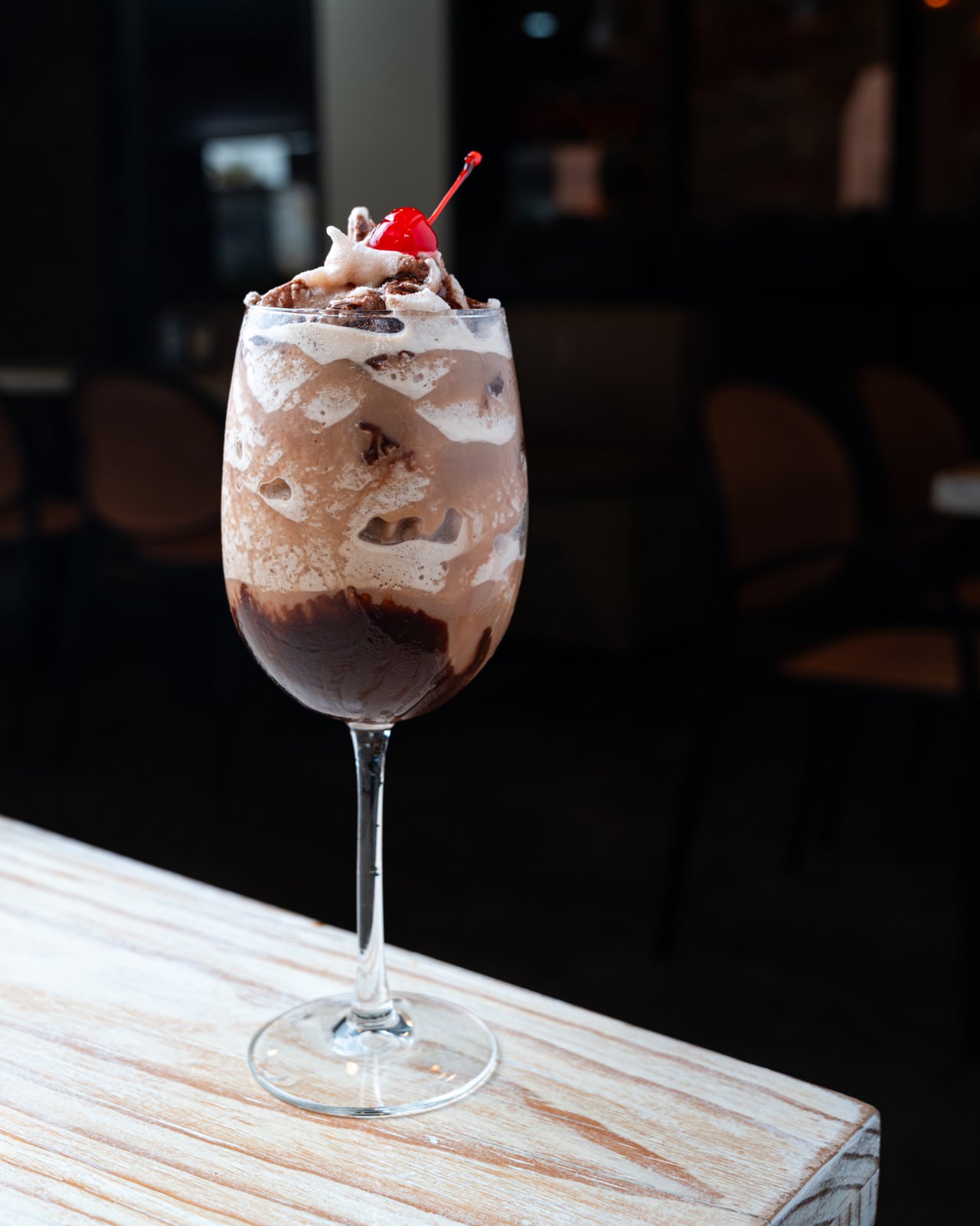 alteada de chocolate con crema batida y cereza en copa de cristal.